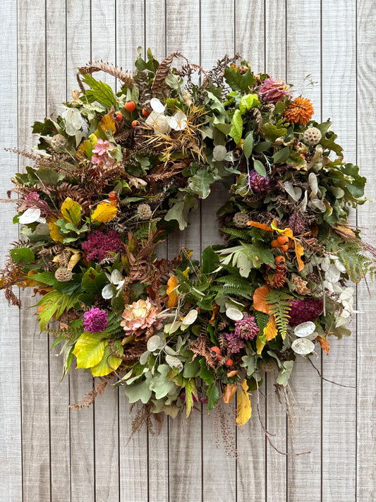 Decorative wreath with greenery and flowers on a wooden background