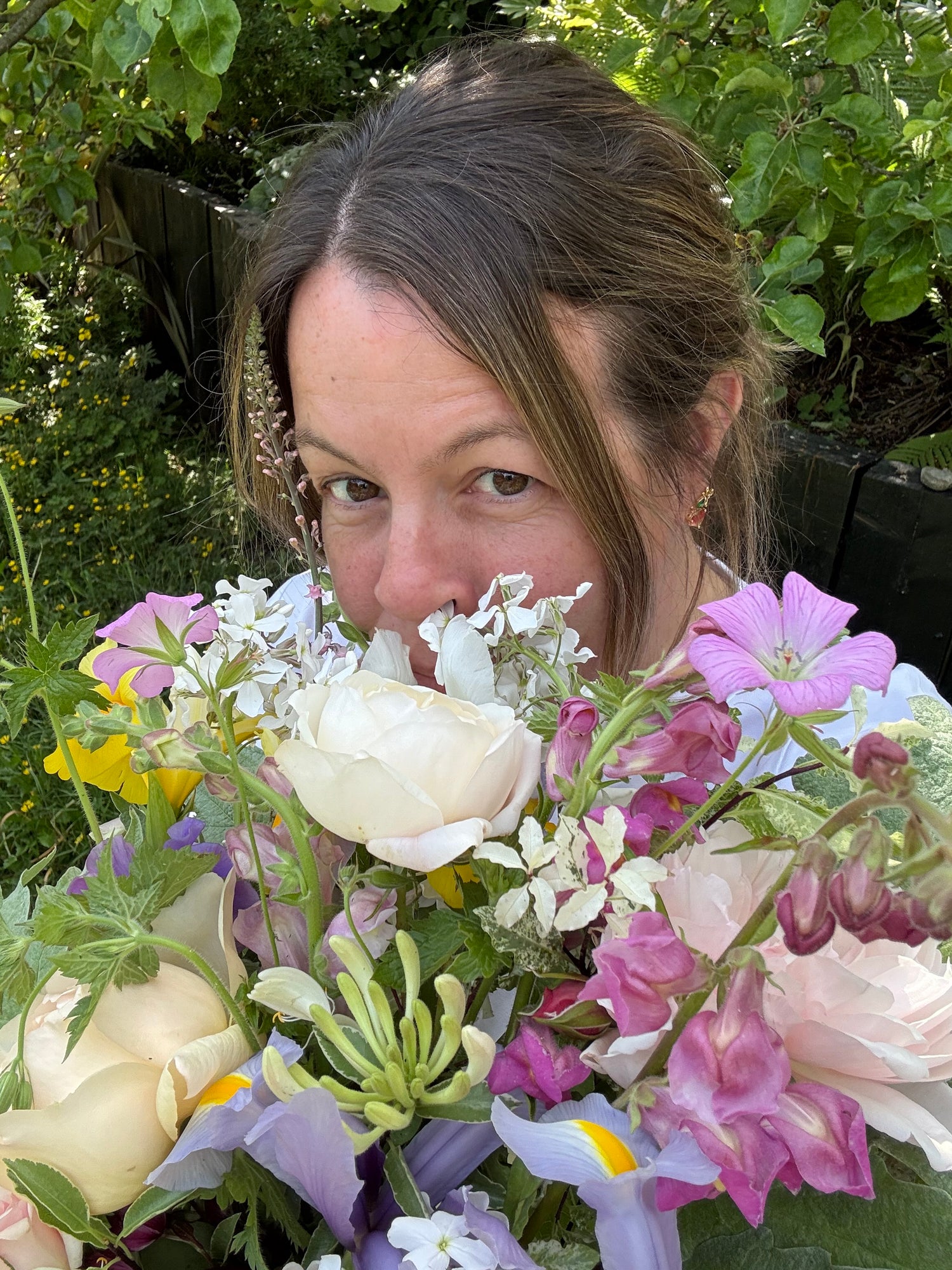 Person smelling spring bouquet with roses, irises and honeysuckle