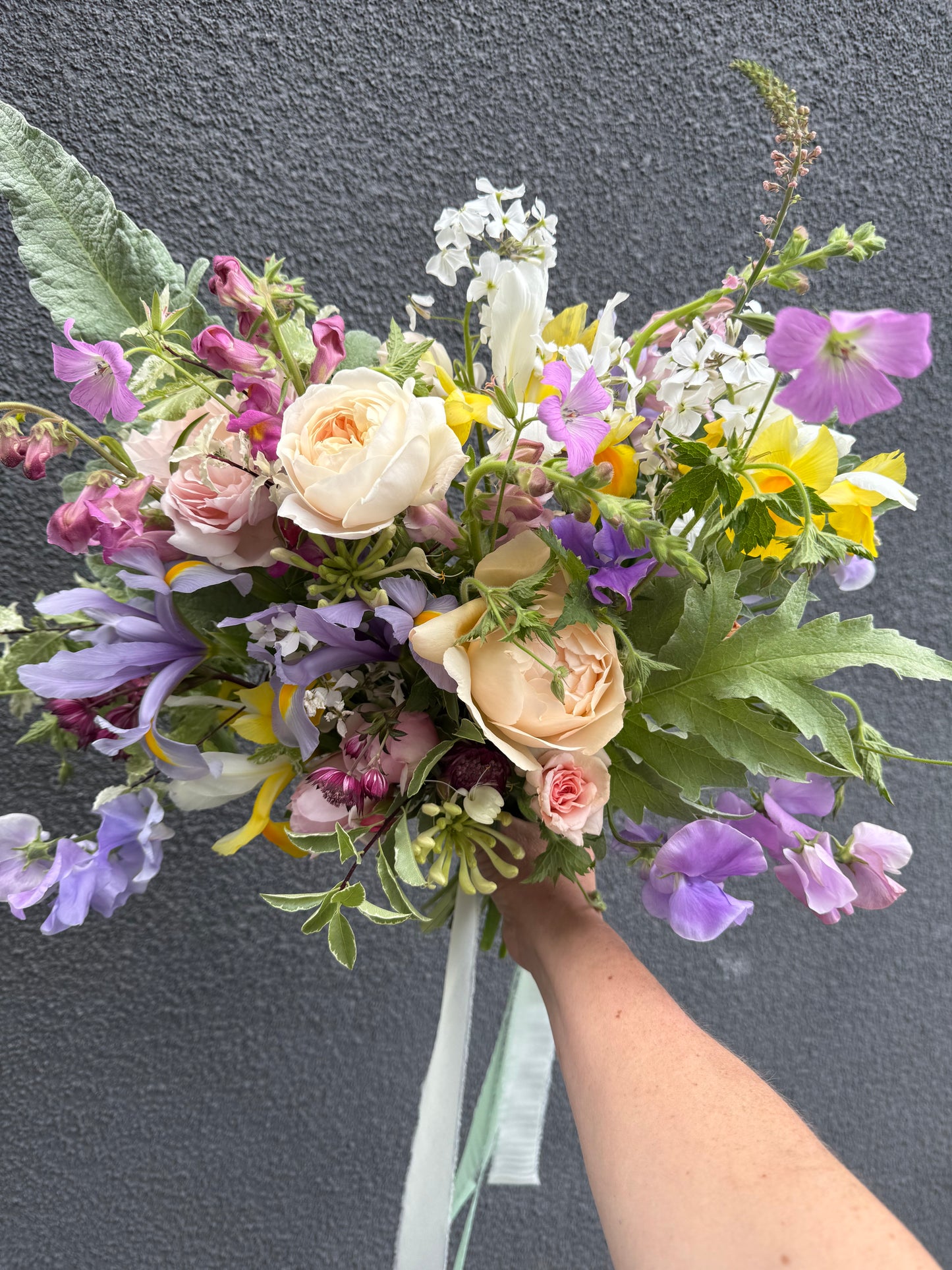 Bouquet of flowers held by a person against a dark background